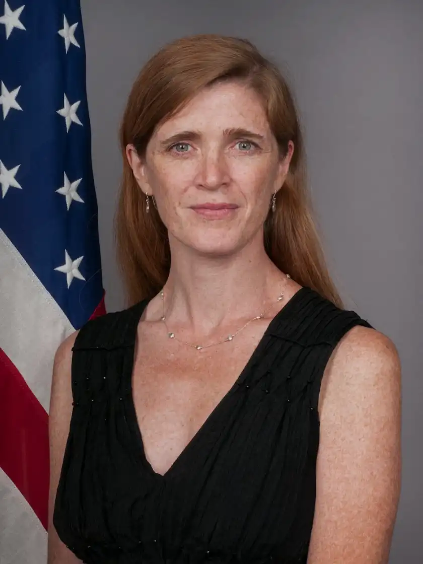 woman in black dress standing by the US flag