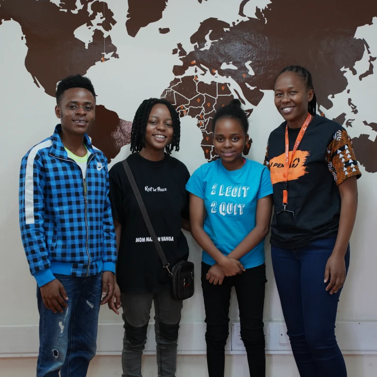 4 people standing in front of a world map