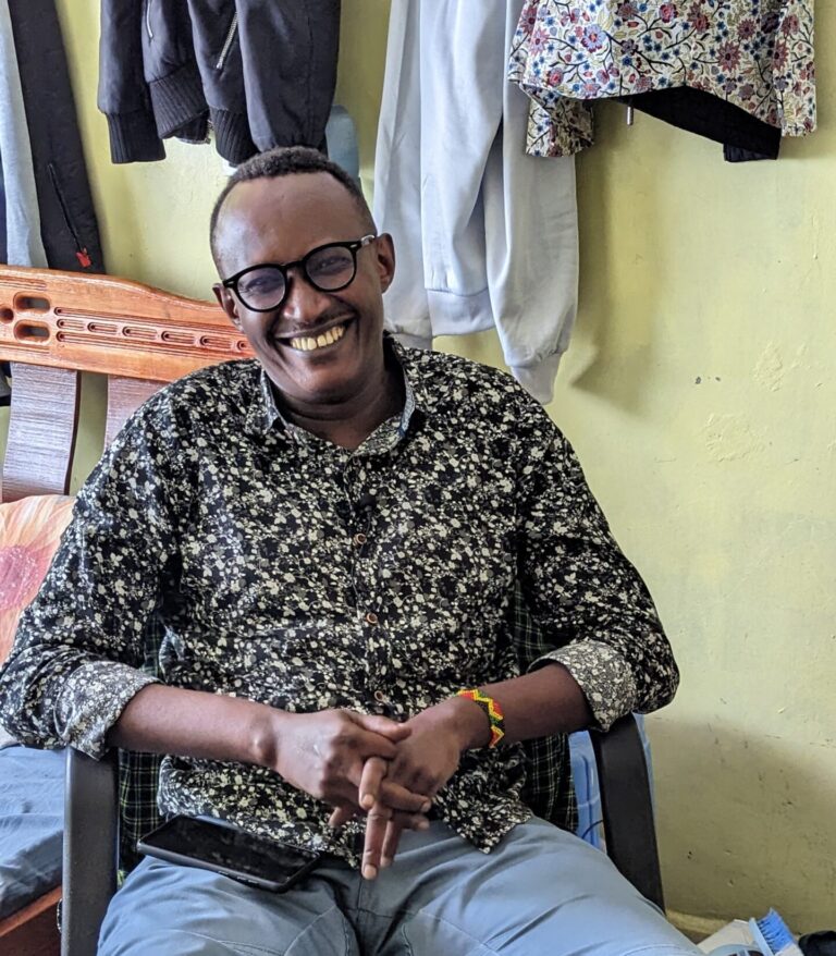 man with glasses smiling as he sits