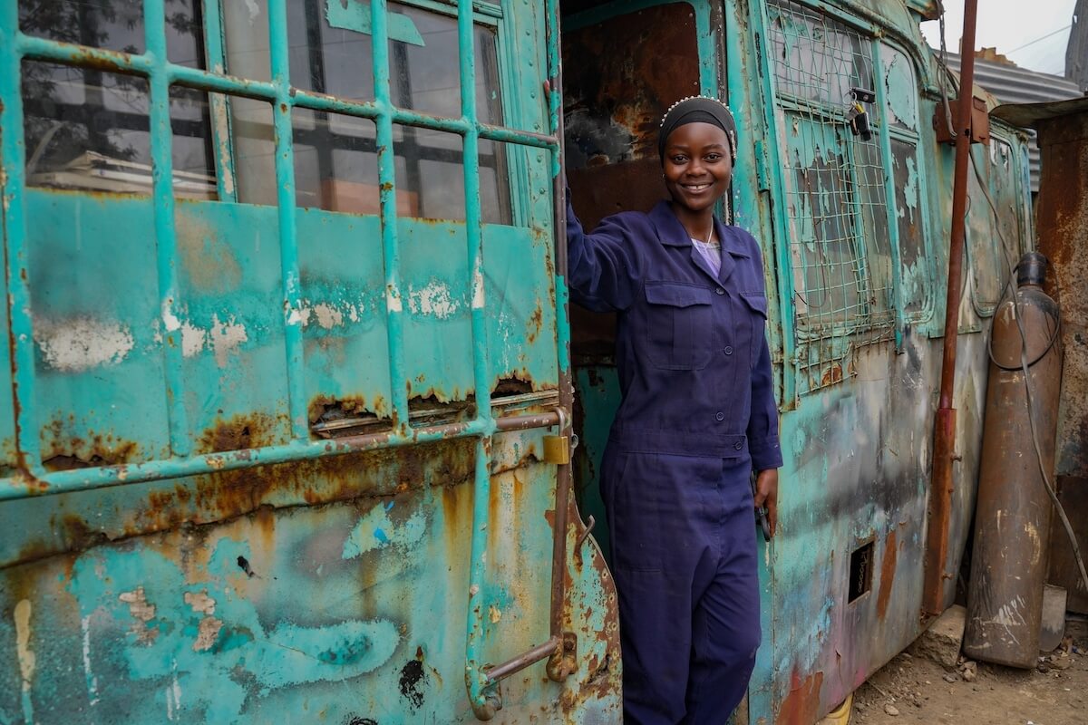 Ugwa stands inside the doors of a blue bus